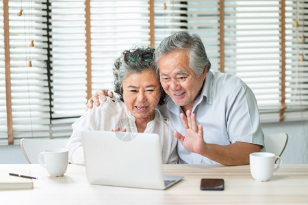 老的快乐亚洲年夫妇在家中用笔记本电脑进行视频聊天和与家人握手微笑的老年人男女一起享受互联网技术在笔记本上一起使用网络技术泰国肖像浪漫高清图片素材