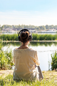 健康瓜拉纳有耳机的女人听柔软音乐在冥想时候早上坐在河前就日出之后清晨坐在河前面早晨高清图片素材