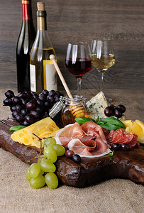 令人满意诺什用肉干熏香肠沙拉米奶酪和葡萄在木制背景上配餐橄榄图片