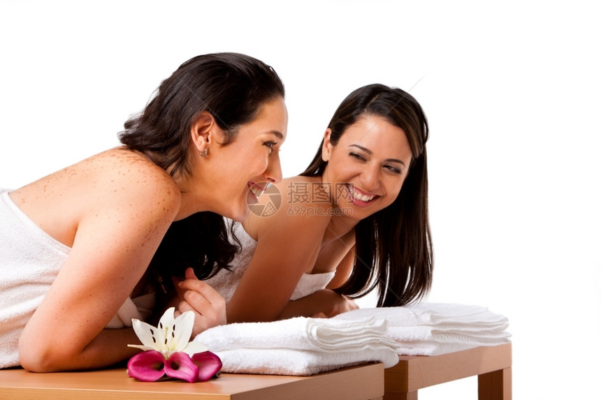 轻松女两个美丽的女朋友躺在木桌上带着毛巾在温泉里等待按摩笑着说话玩得开心与世隔绝花图片
