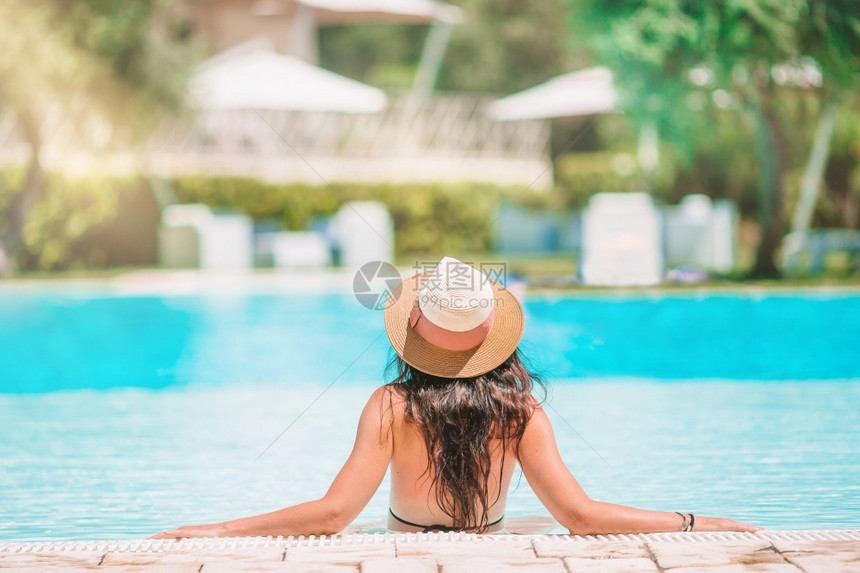 在无边际豪华游泳池享受暑假的年轻美女在豪华游泳池享受暑假的年轻美女吸引人的请享用游泳图片