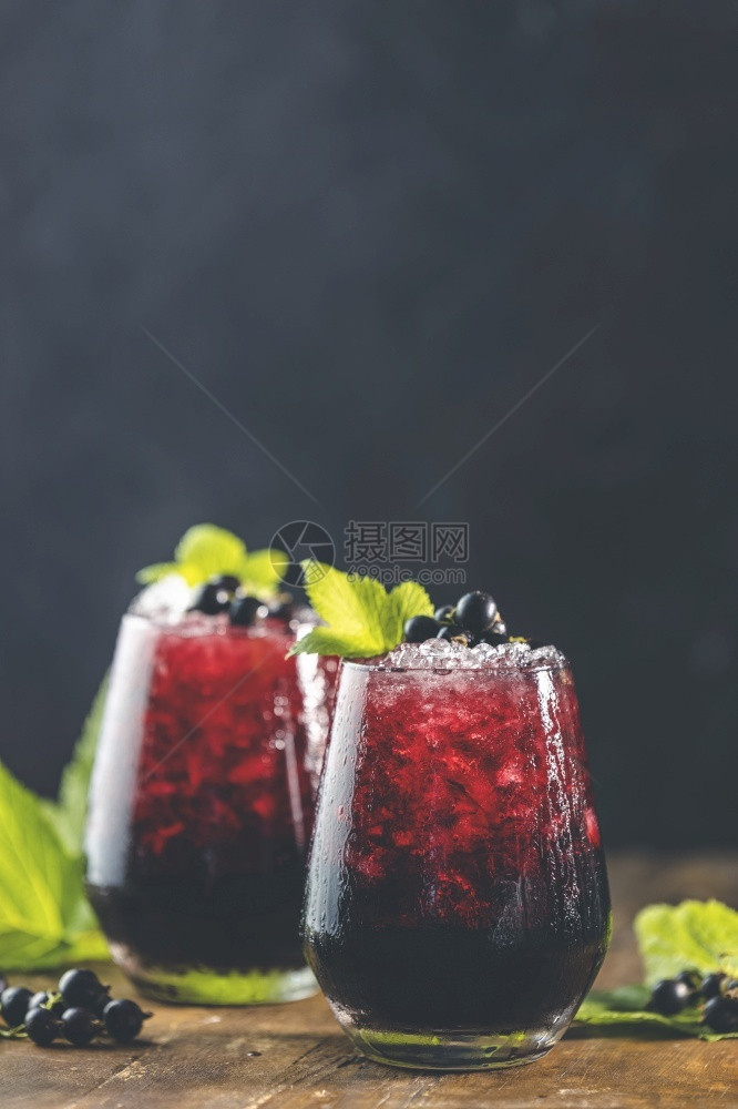 两杯冷冰黑卷曲兰果汁或鸡尾酒加熟浆果和绿叶子放在黑木桌上酒精或非意大利语可口清爽图片