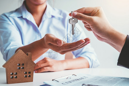 女士向客户提供房屋钥匙和签署购买房地产协议文件的售卖代理商出合同储蓄图片