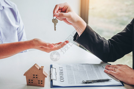 预算合同向女客户提供房屋钥匙和签署购买房地产协议文件的售卖代理商出业解决方案高清图片素材