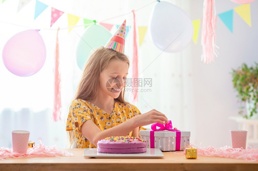 波普尔哨快乐的小女孩解开她现在的生日派对希望概念Festive多彩背景与气球Caucasian女孩充满喜悦的笑容看着生日彩虹蛋糕图片