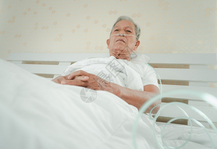 躺在医院病床上并带有鼻喉呼吸管的老年人图片素材