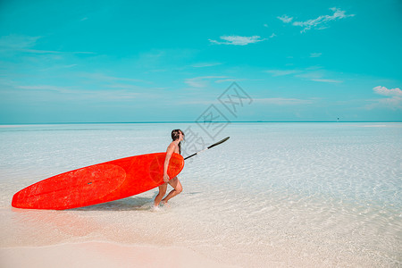 笑美丽的冲浪女子准备在异国情调的假期用红色桨板在绿松石海中冲浪旅行波比基尼高清图片素材