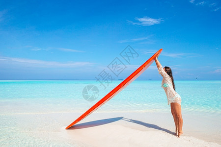胀完美的丽冲浪女子准备在异国情调的假期用红色桨板在绿松石海中冲浪湿的水高清图片素材