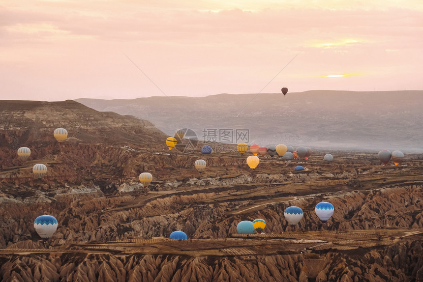 游客空气地标在卡帕多西亚山谷上空飞行的多彩热气球在土耳其流行旅目的地Capapadocia日出时飞过山谷图片