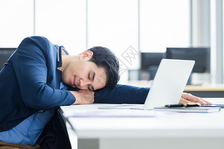 桌子工人亚洲青年商工作到很晚在笔记本电脑上睡着位于办公室背景中睡着了图片