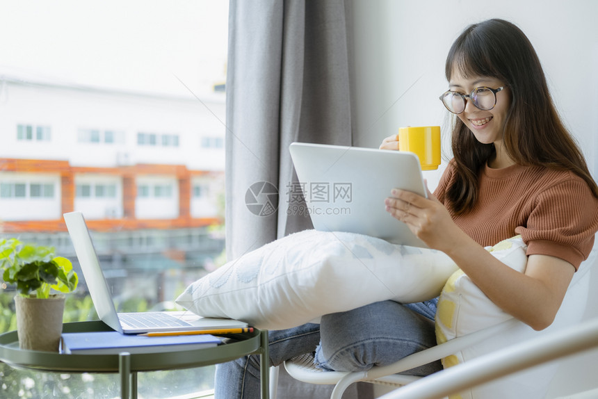 大学软垫移动的使用平板和放松的女青少年在合用空间咖啡厅的椅子上休息在线技术和放松图片