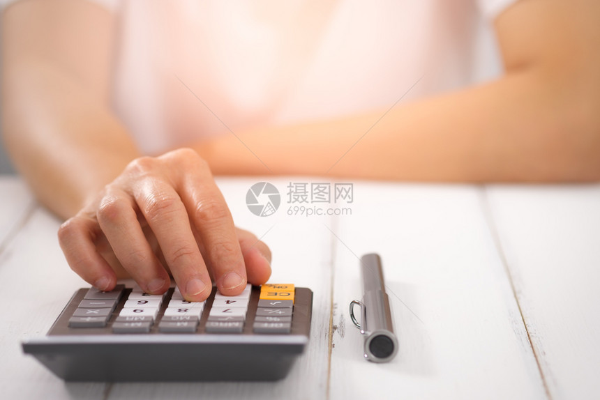 成本使用桌上计算器的女商人选择焦点在光线上钱账单图片