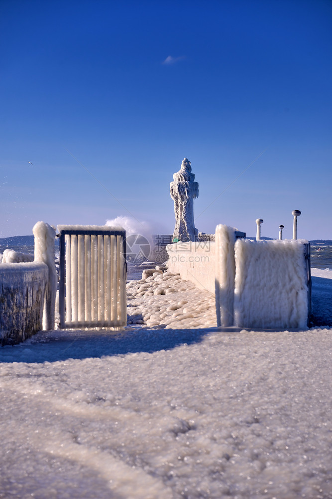 暴风雨戏剧天气寒冷的灯塔和码头在暴风寒冬日图片