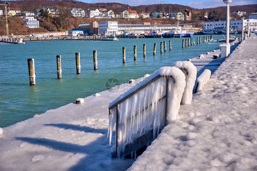 涂层白色的寒冷灯塔和码头在暴风寒冬日冰冷图片