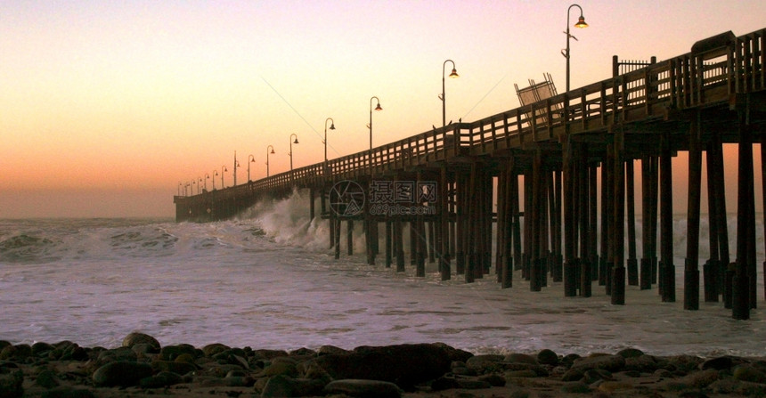 全景横跨海洋的浪暴风雨冲入一个木制码头海滨日落图片