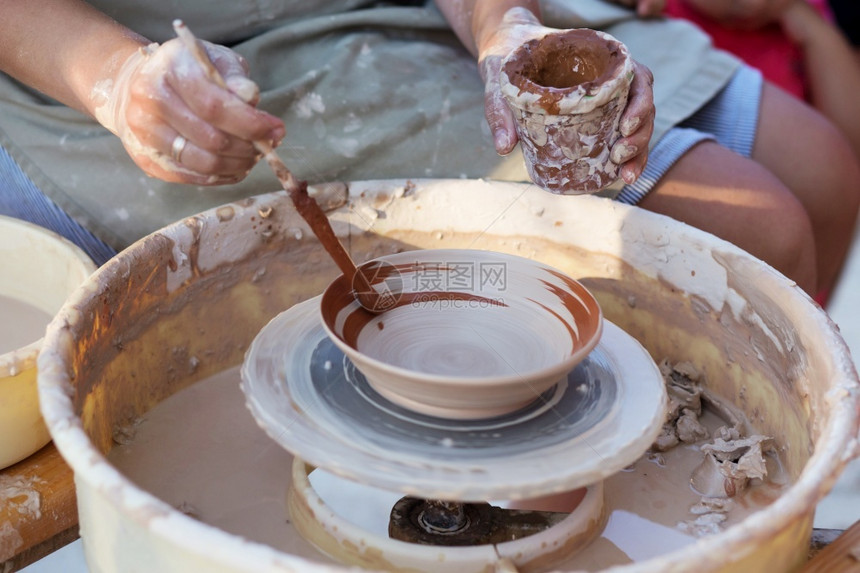 女孩陶匠的手在圆圈上制造一个土罐子艺术创建孩们图片