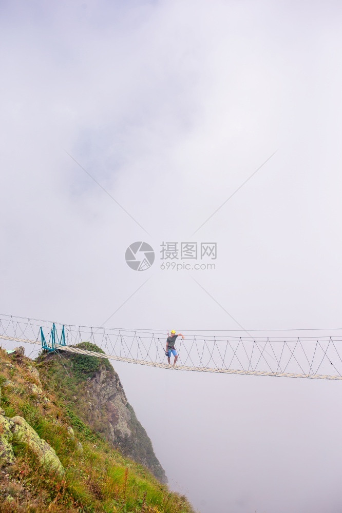 户外位于俄罗斯莎胡托尔山顶的绳桥俄罗斯青年在一座吊桥上横跨山脉深渊俄罗斯莎胡托尔山顶的绳桥游客蓝色图片