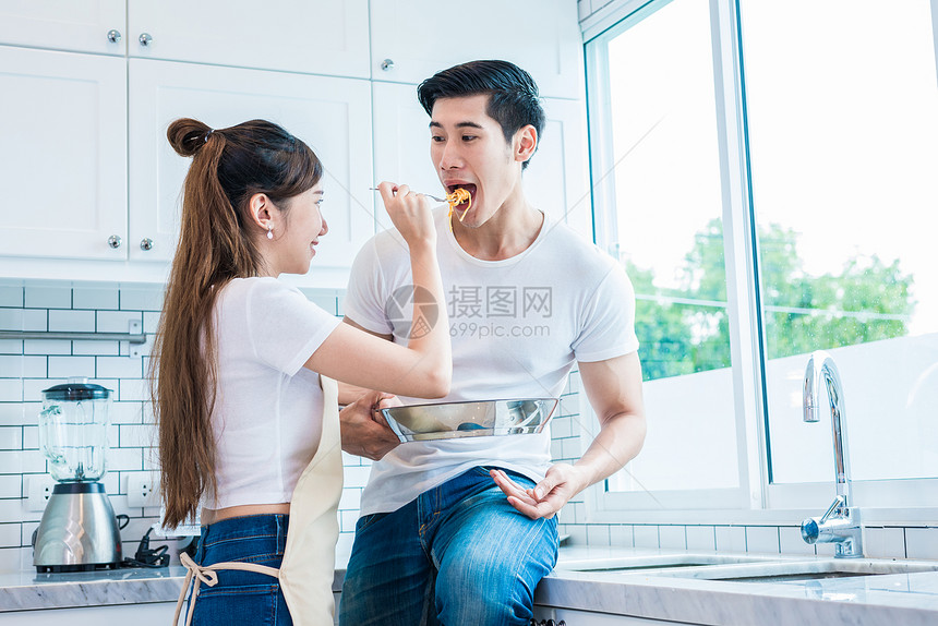 迷人的妇女作为爱或厨房的夫妻向男人提供食物蜜月和婚礼概念烹饪主题手家图片