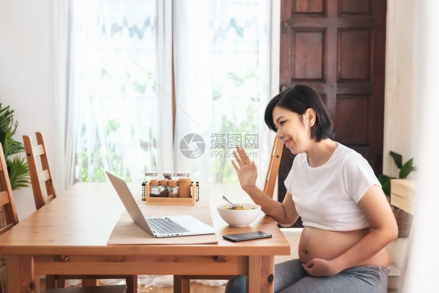 愉快沟通乐笑的亚裔年轻母亲在网上视频电话在她家怀孕时用笔记本电脑聊天和与家人握手时欢乐而美丽的孕妇享受肚子图片