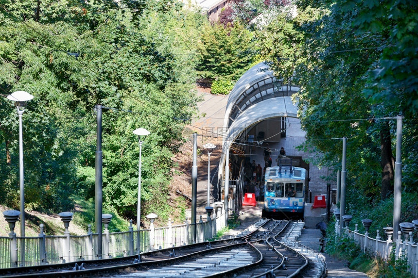 火车包围一辆蓝色和白有线电缆透风车四周环绕着绿色树叶在的遮荫下方一站接客辆蓝色和白有电缆在下边站接客周围有一个夏季绿公园欧洲图片