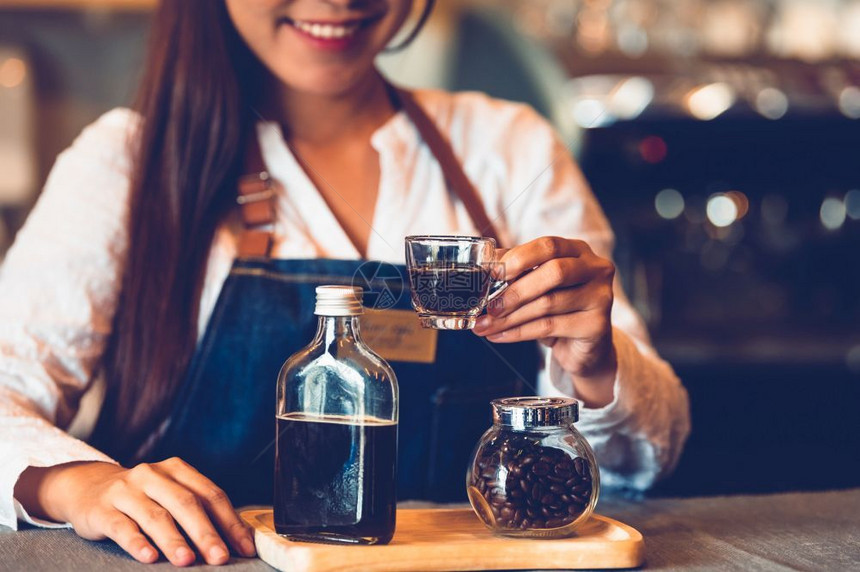 瓶子经理带走关闭咖啡杯以美丽的亚洲妇女咖啡会背景为美貌的咖啡杯为顾客提供咖啡职和业服务食品和饮料咖啡店和餐馆图片