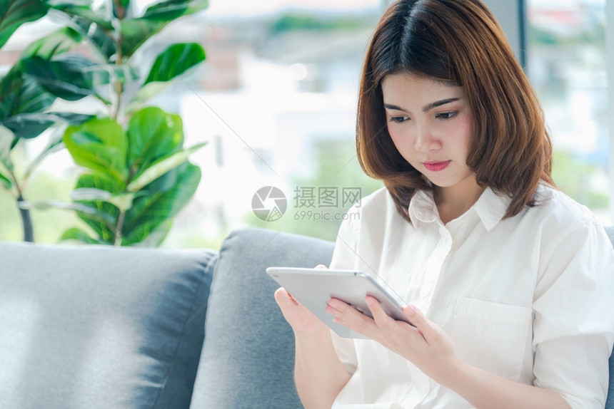 亚裔女使用智能手机阅读网络社交媒体购物网站在Smartphone上微笑脸的智能手机网站上使用智能手机阅读线上社交媒体拥有手机检查图片