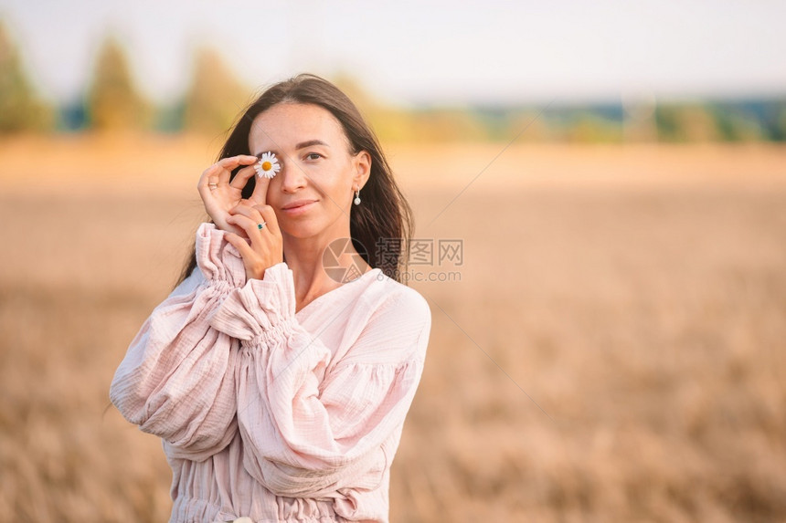 美貌的女人在小麦田里用香菊蒙着眼睛在小麦田里穿着洋装的漂亮女人草帽子有机的图片
