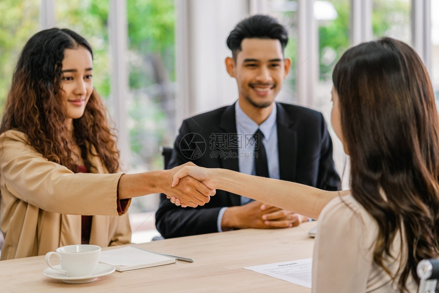 推销员应用亚洲人在年轻妇女与两名在会议室有积极动的经理之间达成面谈协议后密切握手与经理企业雇用新会员概念经理握手并进行接触以及图片