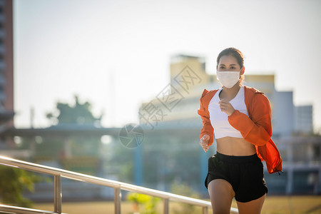 戴口罩跑步户外戴着口罩跑步的年轻女子背景