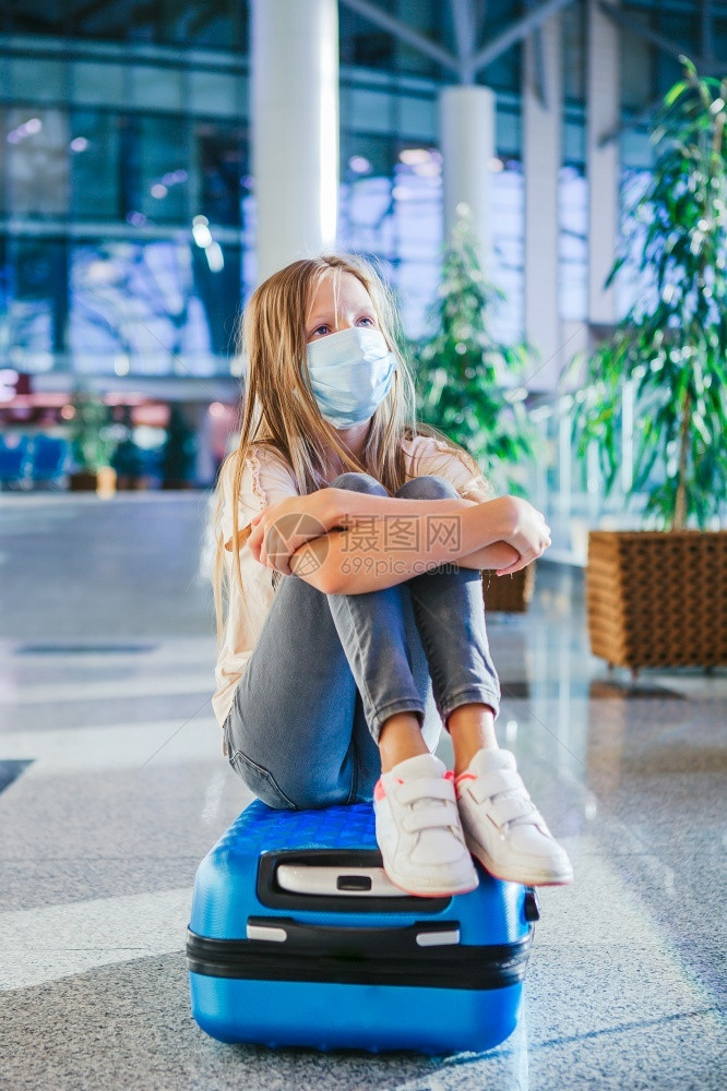 女儿带着外科面具的可爱小孩子在国际机场面临防护保以科罗纳和抓痒小孩戴着医疗面具在机场等待登时被铐着医务面具游客人们图片