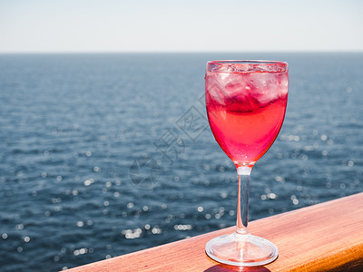 粉色果汁美丽的酒杯有粉红鸡尾酒和冰块在海浪的背景下站在露天的甲板上侧观近距离的休闲概念带着粉红鸡尾酒和冰块旅行马提尼凉爽的甜背景