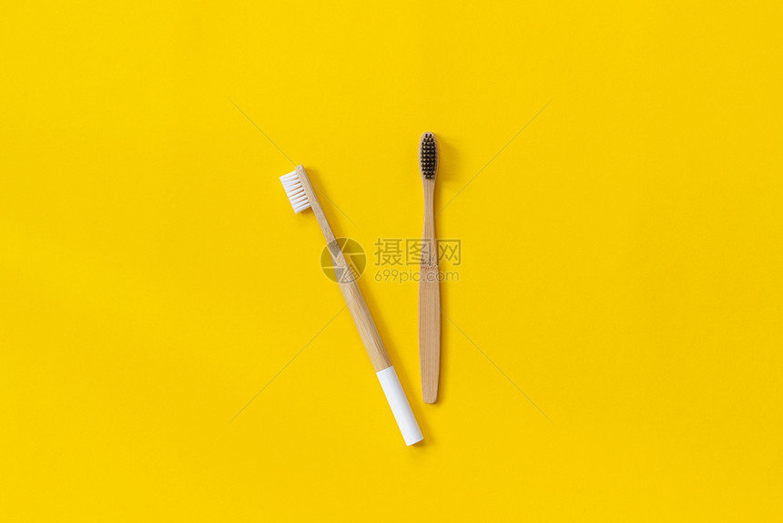 两把天然环保竹刷在纸黄色背景上有白和黑刷毛用于文本或您的设计顶视图平躺牙膏放环保的图片