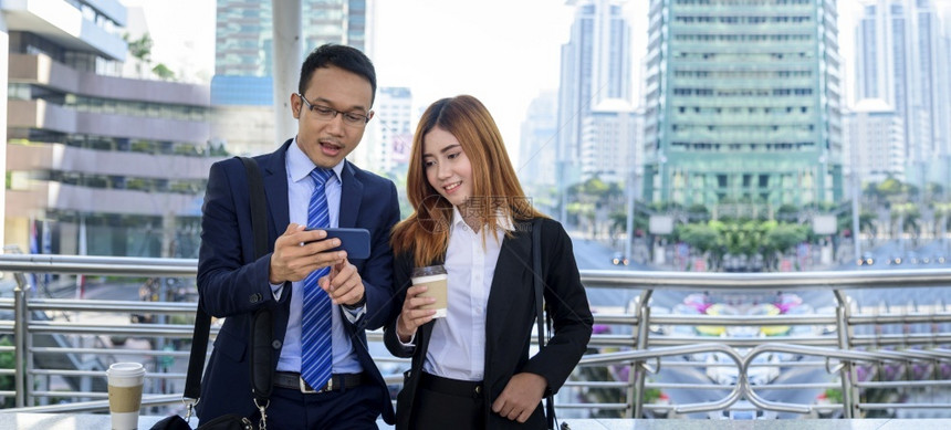 合伙聪明的商业女人在镇上喝咖啡使用智能手机在办公室城外的全景手握着咖啡杯智能电话和商务伙伴乐盘聊天PanoramaHands快乐图片