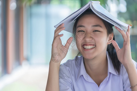 看书的漂亮女孩穿着制服的漂亮女孩亚洲青年大学生在咖啡店阅读情绪轻松的书籍以便在线学习临时商务社交会议或教育概念在咖啡店学习书以放松情绪学习网上背景