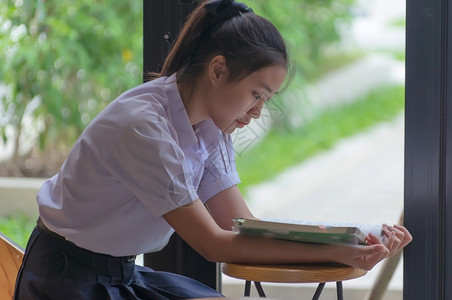 看书的漂亮女孩笔记本电脑图书馆学生们穿着制服的漂亮女孩亚洲青年大学生在咖啡店阅读情绪轻松的书籍以便在线学习临时商务社交会议或教育概念在咖啡店学背景