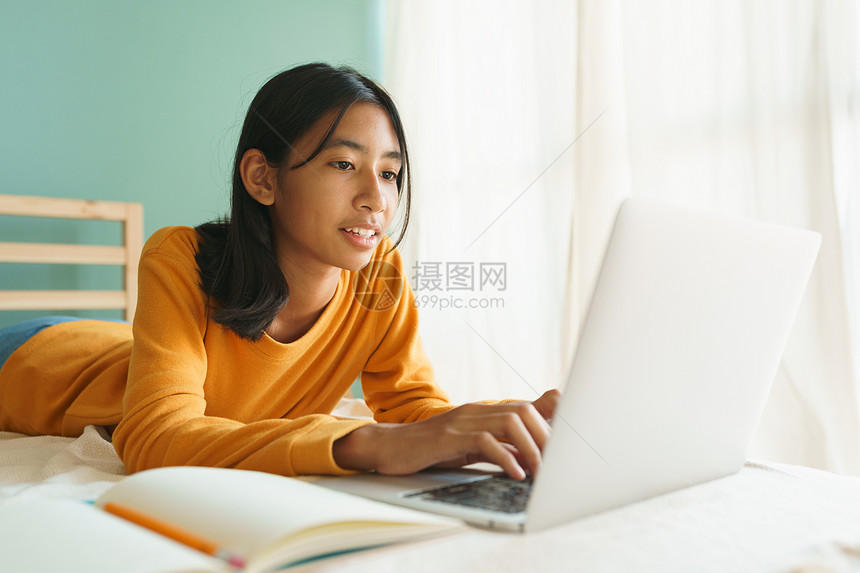 亚洲人工作女在网上学习与一名教师起通过互联网用笔记本电脑在网上学习亚洲女生电视会议在计算机上使用电脑早躺在床概念家庭在线学习女士图片