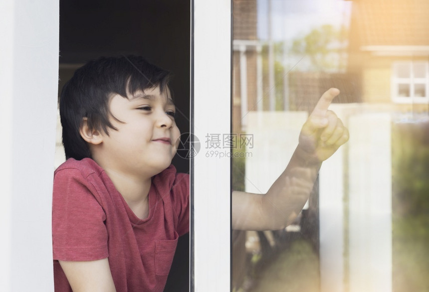 写作坐在窗户边上写着玻璃和微笑脸的阳男孩在QualrantineCovid19期间在家里自孤立的学校儿童在家放松庭教育远程白种人图片