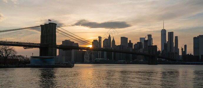 美国市中心天际建筑与交通概念纽约市风景和布鲁克林大桥的现场报道在日落时横跨东河位于美国市区的天际建筑与交通地标都会城市水高清图片素材