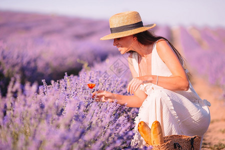 萱衣草夏天紫花衣草地上美丽的年轻女在日落时紫花衣和白帽子下发现了一位红女郎紫色孩背景