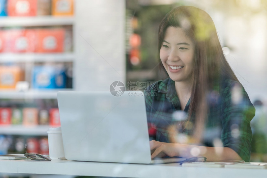 利用技术笔记本电脑在现代办公室玻璃企业主和家概念旁边的办公桌从事幸福行动对临时穿便衣的亚洲女商人进行描写业所有人和企家概念饮料在图片
