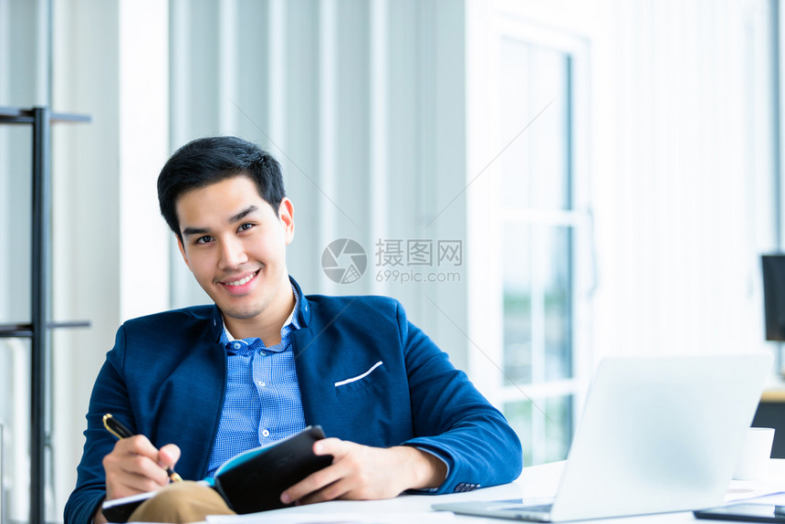 学生制造欢乐的心情一个年轻的亚洲青商人在笔记本和电脑中做的工作在办公室背景中英俊的图片