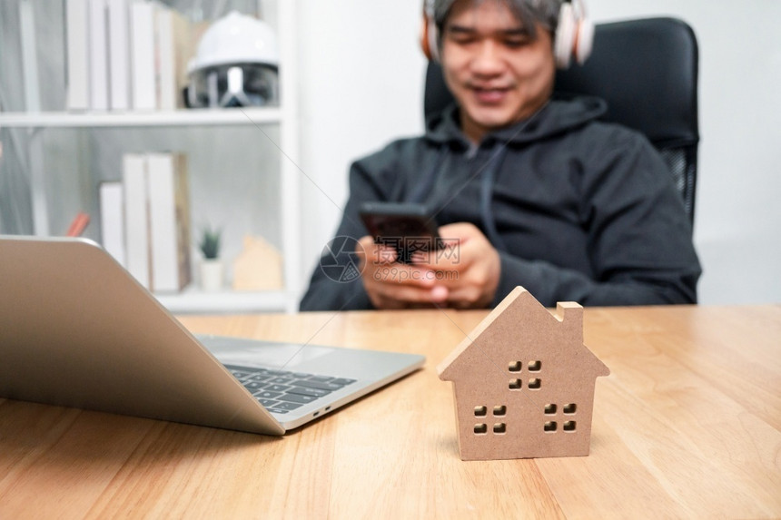 工作区打字以木制房屋为选择焦点微笑的商人打智能手机发送信息从家里工作到CoronaCOVID19隔离快乐的自由职业者工作生活方式图片