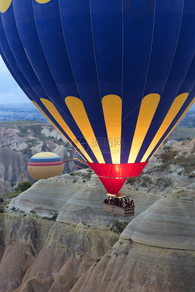 A气球正在飞过卡帕多西亚12058土耳其2058日黎明时分在12058年土耳其的卡帕多西亚山谷上空飞行丰富多彩的形成地质学图片