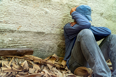 说谎无家可归的人戴着灰色帽子和长袖衬衫因为疲惫而睡着背靠在西门子墙上一种失败背景图片