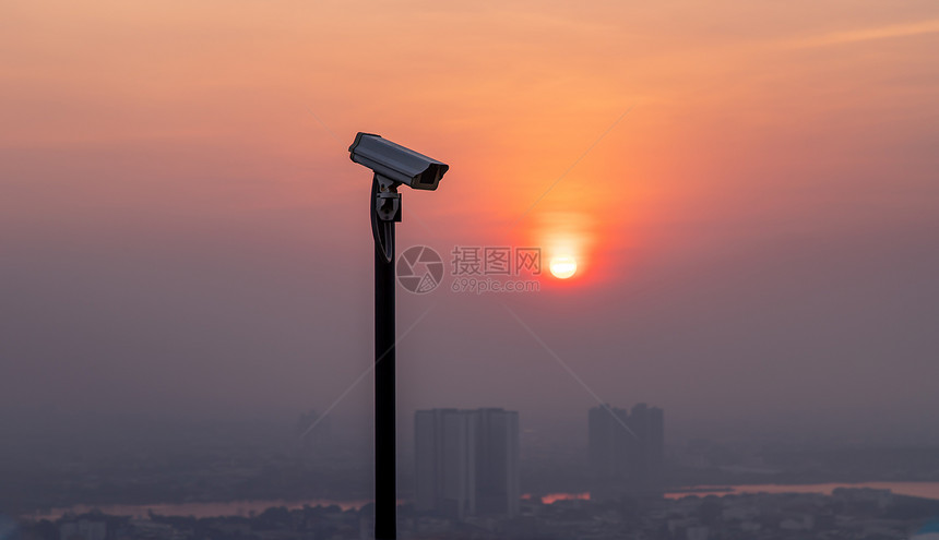 隐私现代监控摄像头拍城市风景和摩天大楼背太阳落下前光闪亮监视晚间时复制空选择焦点的构思重点个人的图片