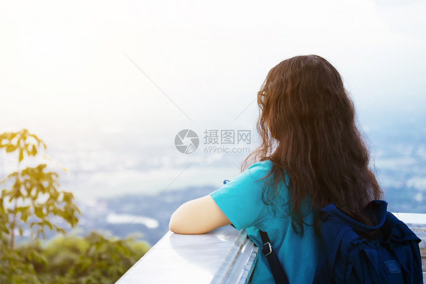 独自的欣赏草地亚洲年轻女子蓝礼服携带便袋旅行者仰慕城市风景山地背观赏城市色图片