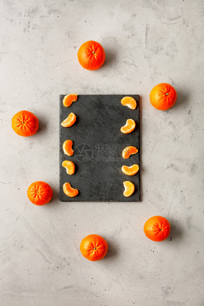 瘦身核有机的橘子亮光和多汁的碎片埋在一块灰色板上周围环绕着整片橙红色橘子位于灰混凝土底部复制空间垂直图像浅亮和多汁的曼达林片落在图片