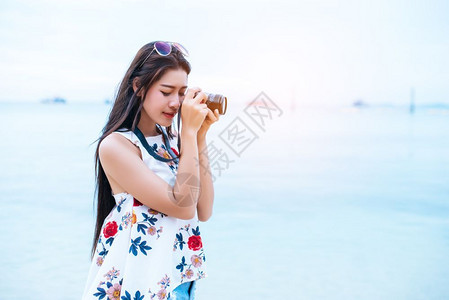年轻的蓝色亚洲女人喜欢在海滩上用数码相机拍照单身和孤独的女人概念幸福和生活方式概念美丽和自然主题海洋背景技术女人节数字的背景图片