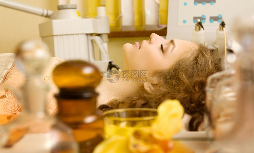 美容师摄影魅力由不同的油瓶和黄色兰花组成的健康温泉前景色上有不同的油瓶和黄色兰花美丽的女在背景上接受美容治疗图片