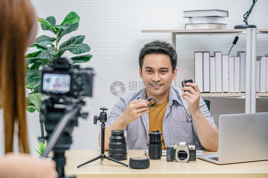 硬件男人营销亚洲Vlogger男子满意每个媒体的相机镜头摄像影机拍视频并用笔记本电脑直播通过社交媒体频道vlog和impactr图片